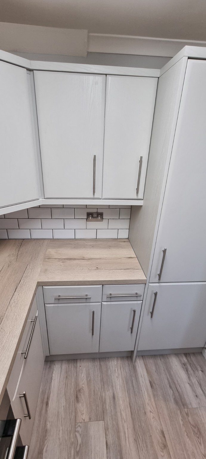 Light grey framed doors, metal bar handles and light wood-effect worktops