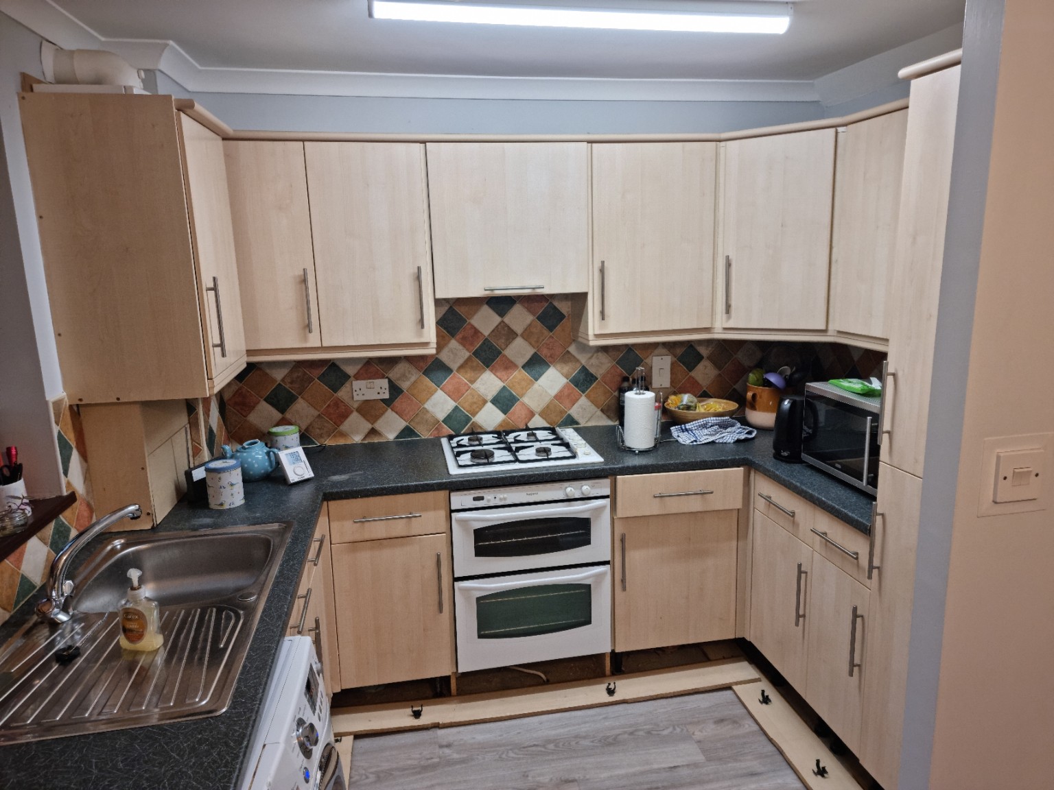 Pale wood-effect doors, dark worktops and multicoloured tiles in the original U-shaped kitchen